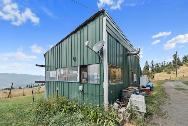 view of side of home featuring dirt driveway, board and batten siding, and a mountain view