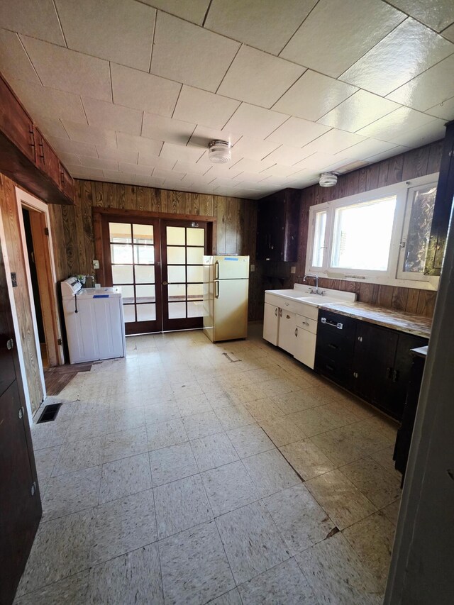 707 N 4th St W, Chewelah, WA 99109 - kitchen with freestanding refrigerator, wood walls, light flooring, light countertops, and french doors