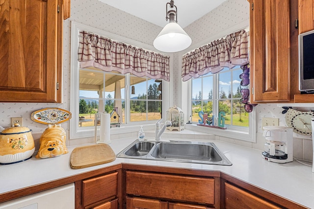 76 Kifer Rd, Kettle Falls, WA 99141 - kitchen with wallpapered walls, light countertops, brown cabinets, and hanging light fixtures