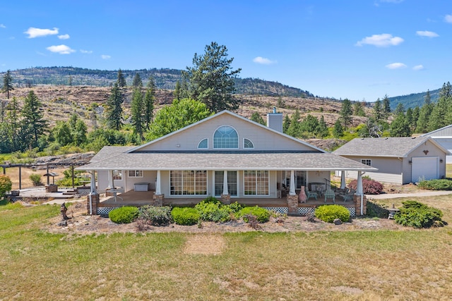 76 Kifer Rd, Kettle Falls, WA 99141 - view of front facade with a porch, a front lawn, a chimney, and a mountain view