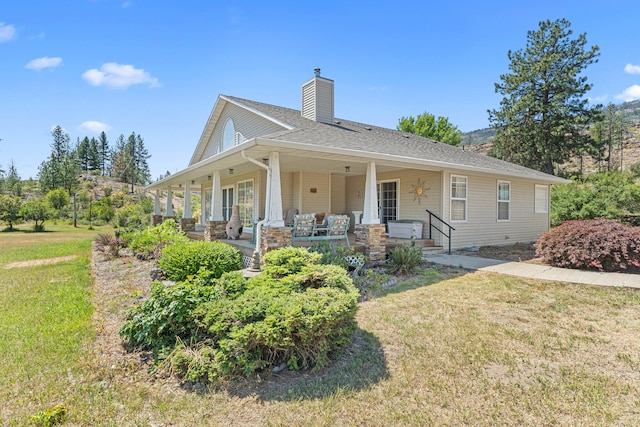 76 Kifer Rd, Kettle Falls, WA 99141 - view of front facade featuring a front lawn, a chimney, roof with shingles, and a porch