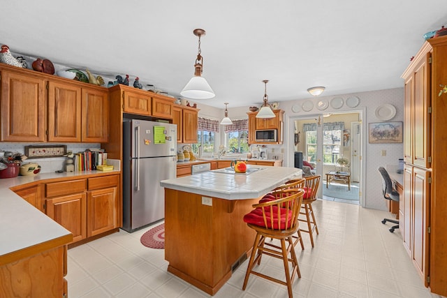 76 Kifer Rd, Kettle Falls, WA 99141 - kitchen featuring appliances with stainless steel finishes, a center island, wallpapered walls, tile countertops, and light flooring