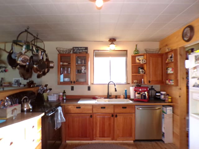 kitchen with brown cabinets, a sink, open shelves, black range with electric cooktop, and dishwasher