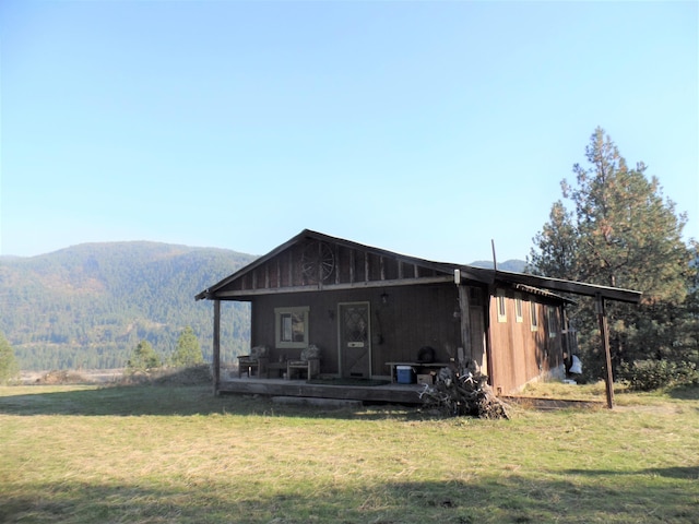 back of house featuring a mountain view and a lawn