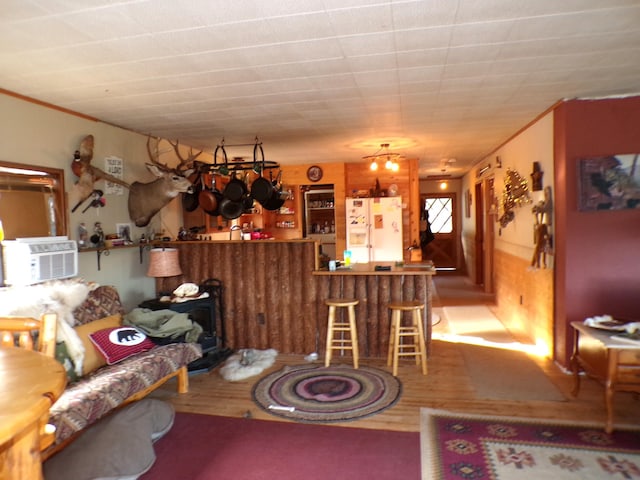 dining space with cooling unit, a dry bar, ornamental molding, and wood finished floors