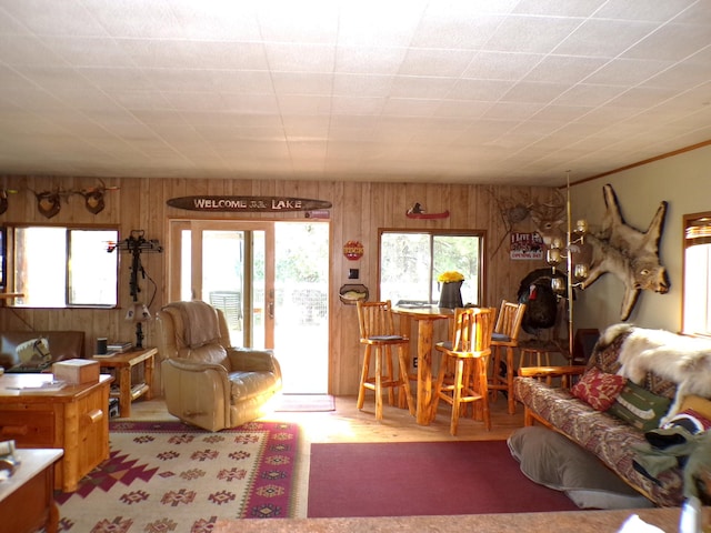 living room featuring crown molding, wood walls, french doors, and indoor bar