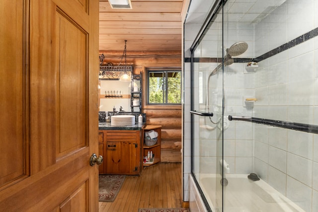 bathroom with vanity, visible vents, wood ceiling, hardwood / wood-style flooring, and enclosed tub / shower combo