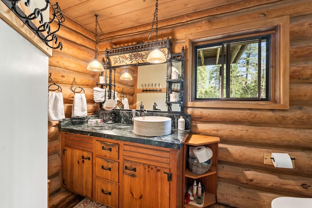 bathroom with wood finished floors, log walls, and vanity