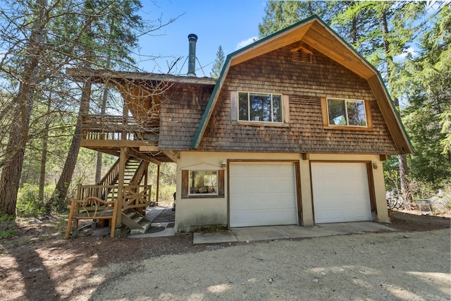 view of front facade featuring a garage, stairs, and a gambrel roof