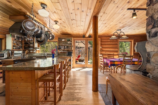 interior space with log walls, dark countertops, wood ceiling, and hardwood / wood-style flooring