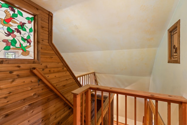 stairs with wooden walls and vaulted ceiling