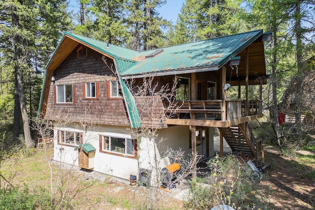 rear view of house featuring a deck, metal roof, and stairs