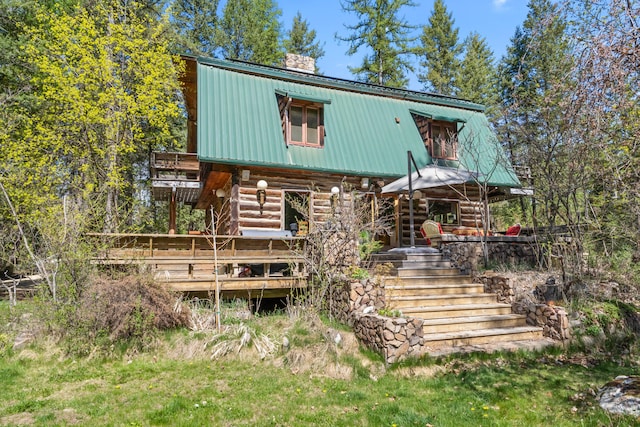 view of front of property featuring metal roof, a chimney, log siding, a wooden deck, and stairs