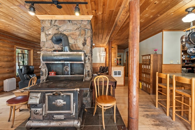 living room featuring visible vents, a wood stove, wooden ceiling, rustic walls, and hardwood / wood-style floors