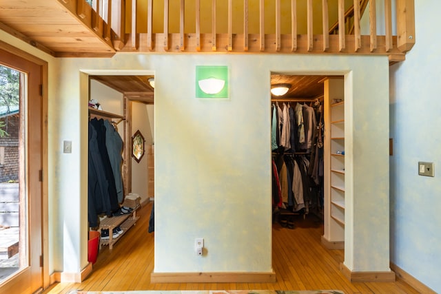unfurnished bedroom featuring light wood-style floors, baseboards, a walk in closet, and a closet