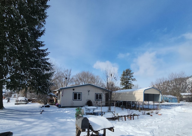 snow covered property with a detached carport