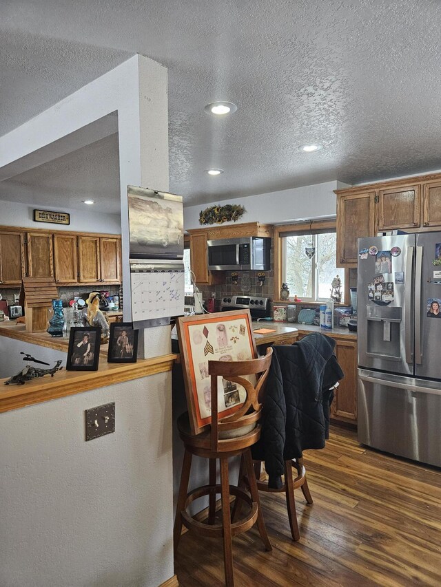 kitchen featuring backsplash, a textured ceiling, appliances with stainless steel finishes, and dark hardwood / wood-style flooring