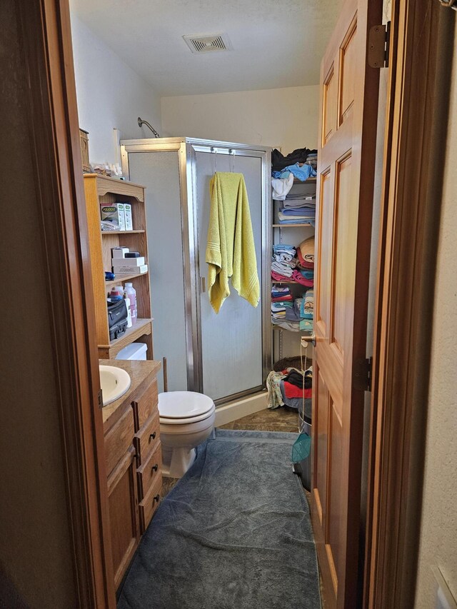 bathroom featuring toilet, a shower with door, and vanity