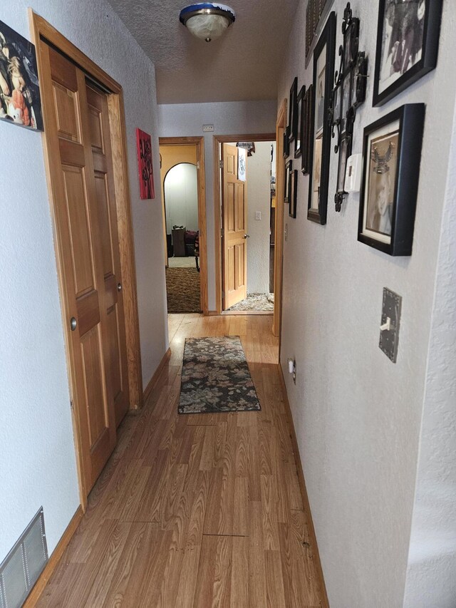 corridor featuring light hardwood / wood-style flooring and a textured ceiling