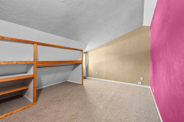 unfurnished bedroom featuring carpet, a closet, vaulted ceiling, and a textured ceiling