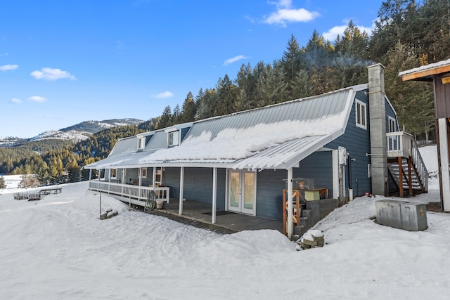 snow covered back of property with a mountain view