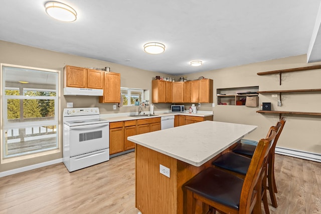 kitchen with sink, white appliances, a breakfast bar, and a healthy amount of sunlight