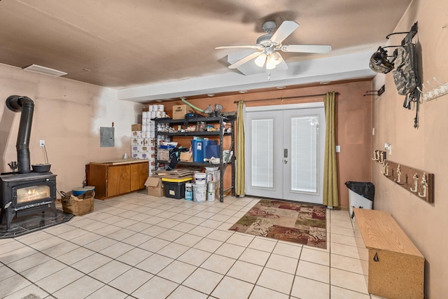 foyer entrance featuring electric panel, light tile patterned floors, a wood stove, ceiling fan, and french doors