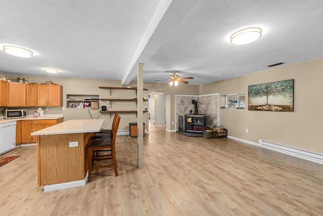 kitchen featuring a wood stove, a center island, light hardwood / wood-style floors, white dishwasher, and a kitchen breakfast bar