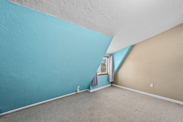 bonus room featuring carpet, vaulted ceiling, and a textured ceiling