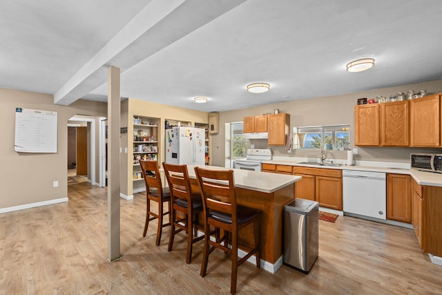 kitchen featuring white appliances, sink, a center island, a kitchen breakfast bar, and light hardwood / wood-style floors