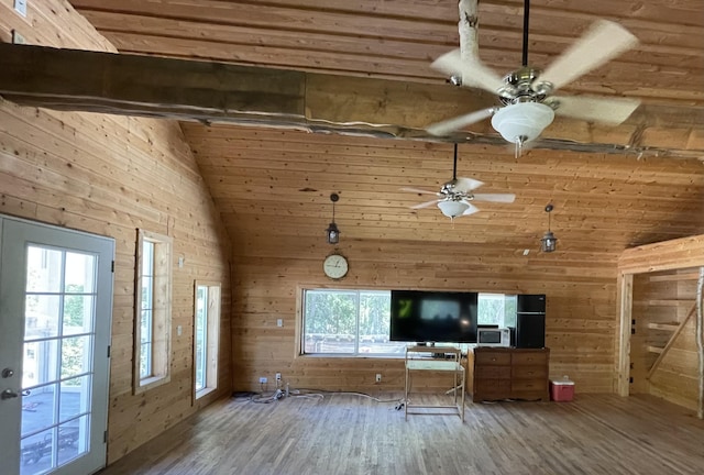unfurnished living room with wooden walls, high vaulted ceiling, a ceiling fan, and wood finished floors