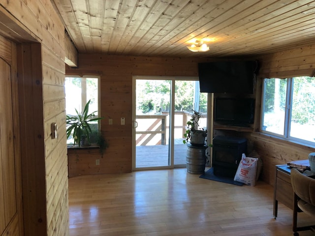 doorway to outside featuring hardwood / wood-style flooring, wood walls, wooden ceiling, and a wood stove