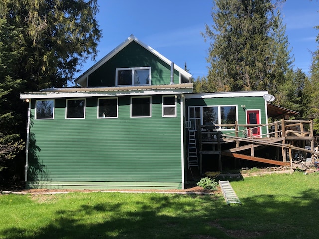 back of house featuring a wooden deck, a yard, and metal roof