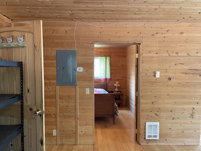hall featuring wood walls, visible vents, light wood-style flooring, and electric panel