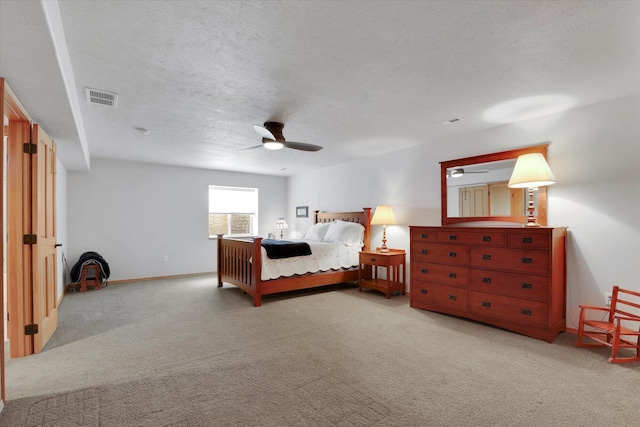 bedroom with ceiling fan, light colored carpet, a textured ceiling, baseboards, and visible vents