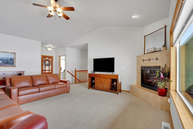 living room featuring lofted ceiling, light colored carpet, a premium fireplace, a ceiling fan, and visible vents