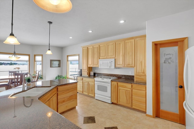 kitchen featuring recessed lighting, a sink, light brown cabinetry, and white appliances