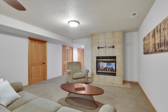 living area featuring carpet floors, a textured ceiling, visible vents, and a tile fireplace