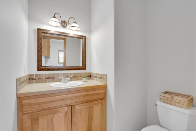 half bathroom featuring vanity, decorative backsplash, and toilet