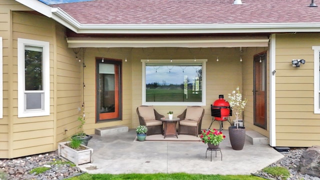 doorway to property with roof with shingles and a patio