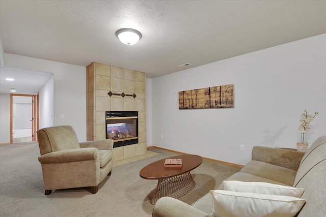 living room with visible vents, a fireplace, baseboards, light colored carpet, and a textured ceiling