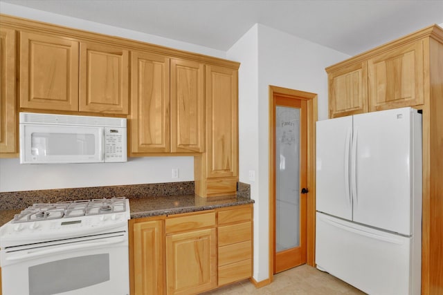 kitchen featuring dark stone counters and white appliances