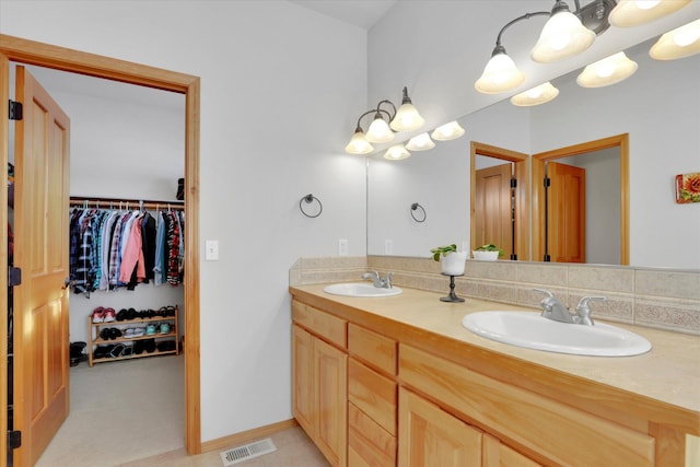 bathroom with a sink, a spacious closet, double vanity, and visible vents