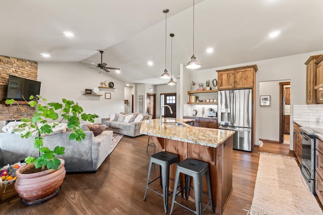 31914 N Zander Ln, Chattaroy, WA 99003 - kitchen featuring stainless steel appliances, a sink, open floor plan, brown cabinets, and vaulted ceiling