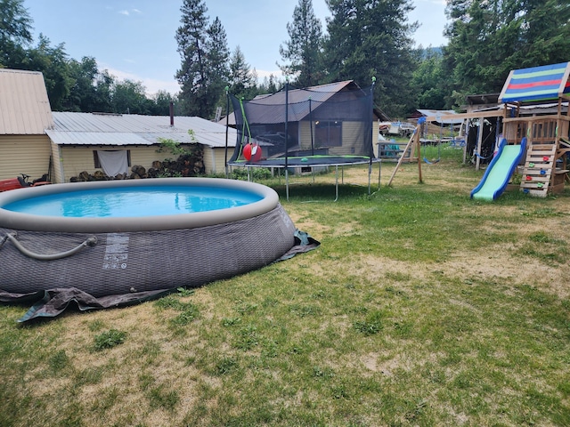 view of pool featuring a lawn, a playground, and a trampoline