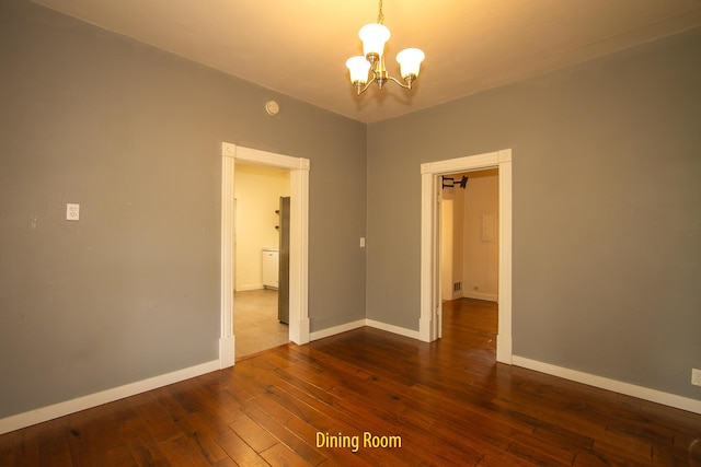 spare room featuring an inviting chandelier and dark hardwood / wood-style flooring