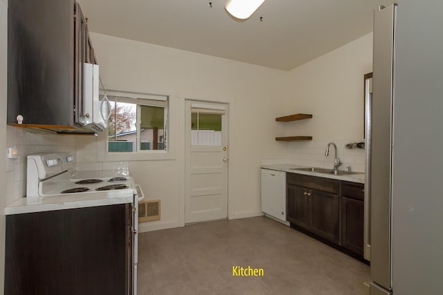 kitchen with dark brown cabinetry, sink, white appliances, and decorative backsplash