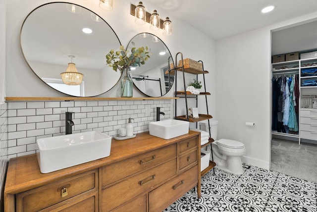 2419 Indian Ridge Rd, Chewelah, WA 99109 - full bath featuring double vanity, toilet, a spacious closet, decorative backsplash, and recessed lighting