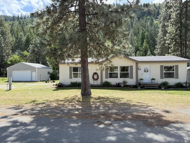 ranch-style home with a garage, a front yard, an outbuilding, and driveway