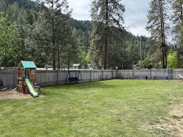 view of yard featuring a playground and a wooded view